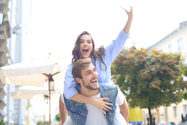 Przystojny młody mężczyzna niosący młodą atrakcyjną kobietę na ramionach podczas wspólnego spędzania czasu na świeżym powietrzu.