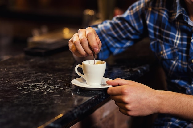 Przystojny młody mężczyzna pije i cieszy kawę siedząc przy barze w kawiarni miejskiej