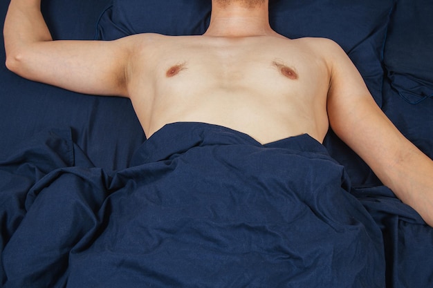 Przystojny młody mężczyzna śpiący wygodnie na łóżku w nocy w swojej sypialni bez ubrania Sypialnia kawalerska Głęboki sen