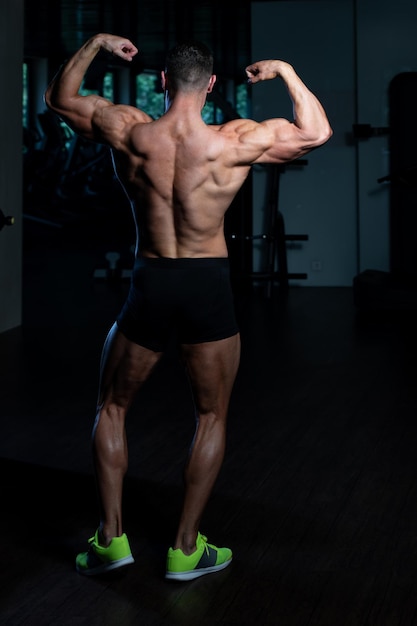 Przystojny Młody Mężczyzna Stojący Silny Na Siłowni I Napinanie Mięśni Mięśni Atletyczny Kulturysta Model Fitness Pozuje Po Ćwiczeniach