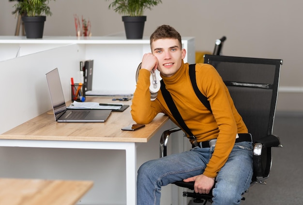 Przystojny młody mężczyzna ze słuchawkami siedzi w białym, czystym biurze