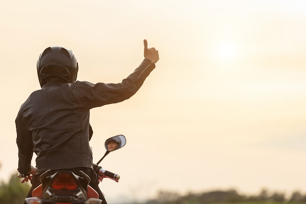 Przystojny motocyklista nosić skórzaną kurtkę, trzymając hełm na drodze