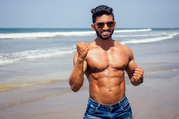 Przystojny muskularny ciemnowłosy surfer sportowy muskularny i zdrowy murzyn na plaży podczas letniego poranka rozgrzewka ocean indie morze wakacje Goa