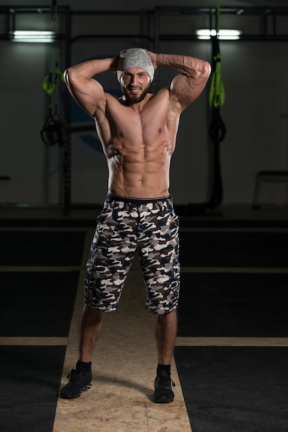 Przystojny muskularny mężczyzna napina mięśnie na siłowni