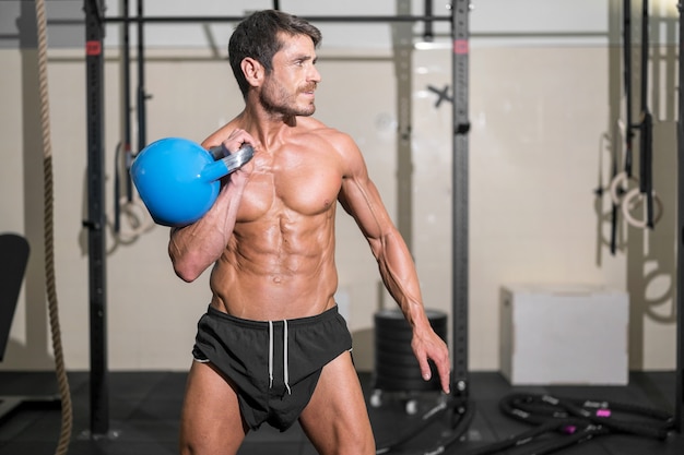 Przystojny muskularny mężczyzna podnoszący ciężki kettlebell