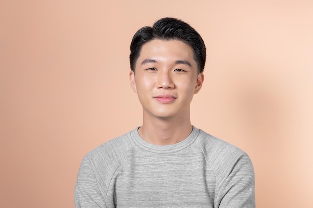 Przystojny portret młodego azjatyckiego mężczyzny uśmiechającego się na białym tle na beżowym tle