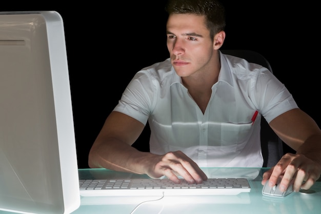 Przystojny skupiający się komputerowy inżynier pracuje przy nocą
