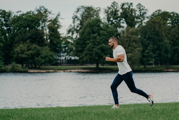 Przystojny Sportowiec Brodaty Mężczyzna Biega Na Zewnątrz W Porannych Pozach W Pobliżu Rzeki Cieszy Się Naturą I świeżym Powietrzem Demonstruje Wytrzymałość I Motywację Ma Poranny Trening Każdego Dnia Pozostaje Sprawny Zdrowy Silny