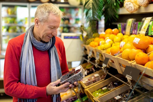 Przystojny starszy mężczyzna wybierający świeże organiczne owoce w supermarkecie