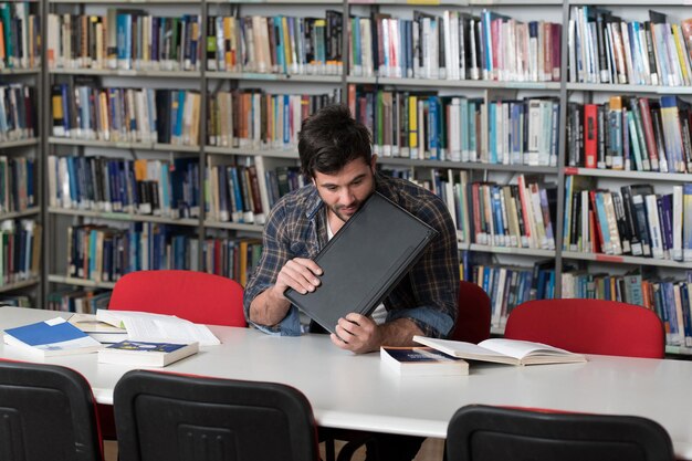 Przystojny student rzucający laptopem i chcący go zniszczyć