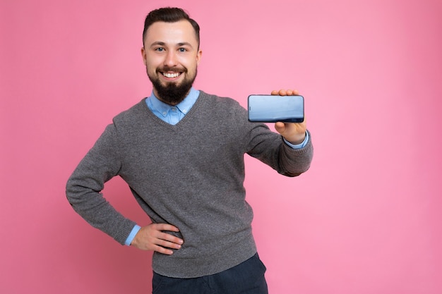 Przystojny szczęśliwy fajny młody brunetka nieogolony mężczyzna z beardwearing stylowym szarym swetrem i