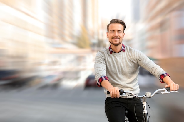 Przystojny szczęśliwy mężczyzna jazda rowerem na efekt rozmycia ruchu ulicy miasta