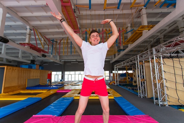 Przystojny szczęśliwy mężczyzna skaczący na trampolinie w pomieszczeniu.