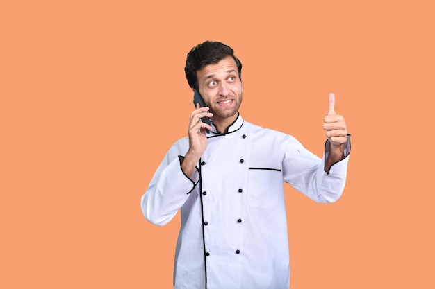 przystojny szef kuchni rozmawia przez telefon biały strój indyjski pakistański model