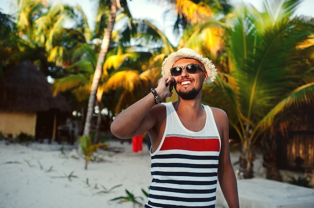 Przystojny turysta mężczyzna rozmawia na smartfonie na tle palm