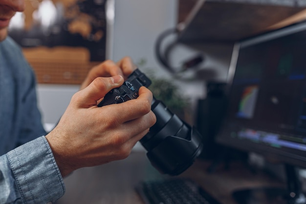 Zdjęcie przytnij człowieka z profesjonalnym aparatem fotograficznym w rękach w domowym biurze