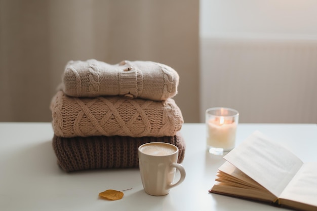 Przytulna, komfortowa domowa atmosfera hygge i martwa natura z książką na filiżanki i swetrami