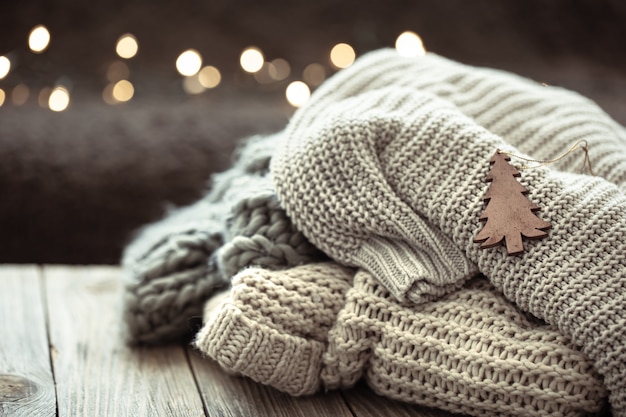 Zdjęcie przytulna kompozycja świąteczna ze stosem swetrów z dzianiny na rozmytym tle z bokeh.