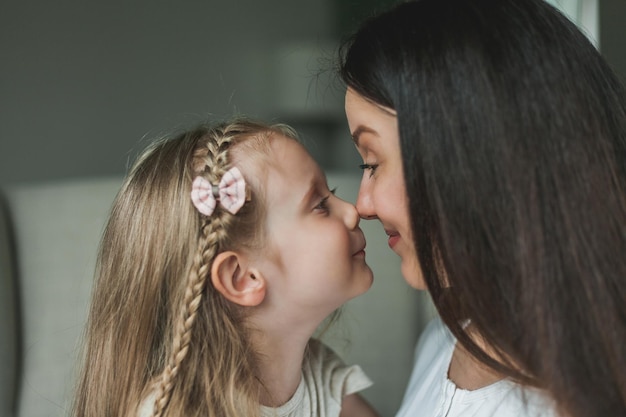 Przytulny domowy portret młodej, pięknej, ciemnowłosej matki i jej 4-letniej córki o długich, lśniących włosach Relacje rodzinne Miłość