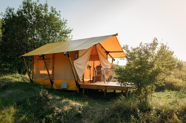 Przytulny otwarty namiot glampingowy ze światłem w środku podczas zachodu słońca Luksusowy namiot kempingowy na letnie wakacje na świeżym powietrzu i wakacje Koncepcja stylu życia
