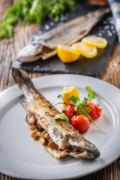 Pstrąg rybny z grzybami i warzywami na talerzu w hotelu lub restauracji.