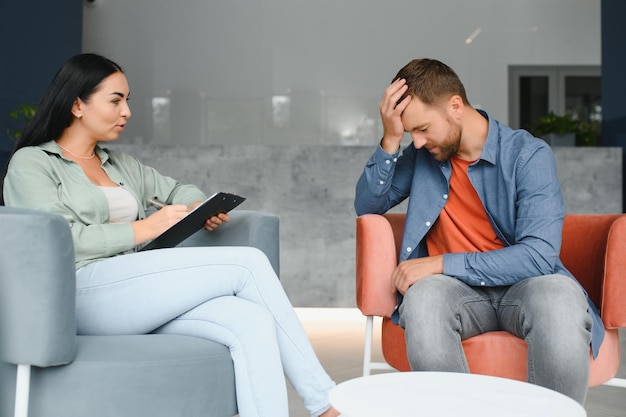 Psychologia psychoterapia i koncepcja ludzi kobieta psycholog rozmawia ze smutnym młodym pacjentem podczas sesji psychoterapii