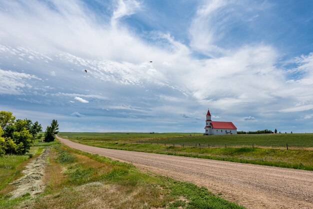 Ptaki Przelatujące Nad żwirową Drogą W Kraju Prowadzącym Do Zabytkowego Kościoła Rzymskokatolickiego St. Martins W Billimun, Saskatchewan, Kanada