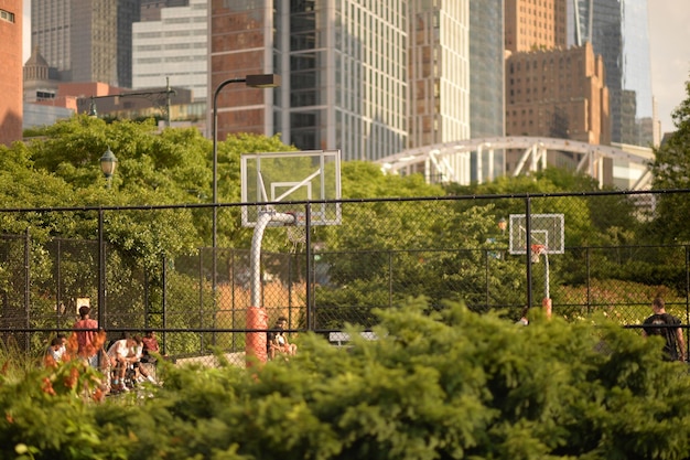 Publiczne boisko do koszykówki z nowoczesnymi drapaczami chmur na tle