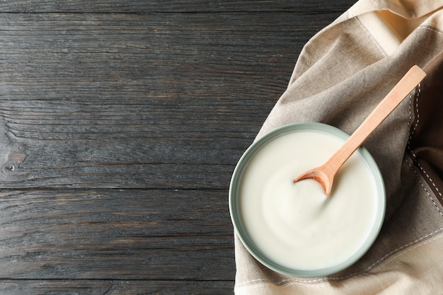 Puchar jogurt, łyżka i ręcznik kwaśnej śmietany na drewniane tła