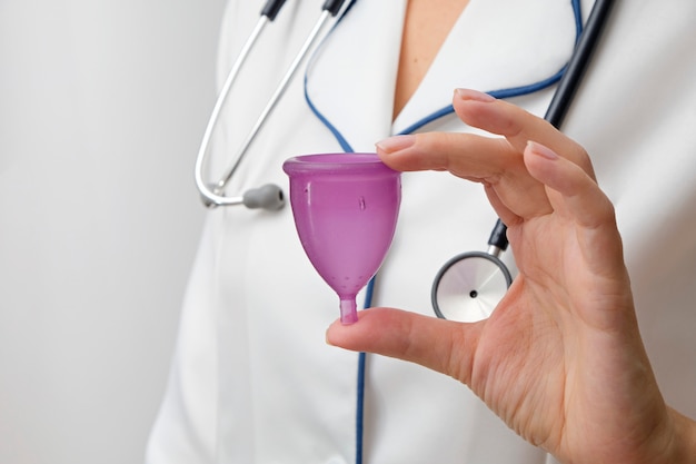 Puchar menstruacyjny w dłoni lekarza, zbliżenie, koncepcja zdrowia kobiet