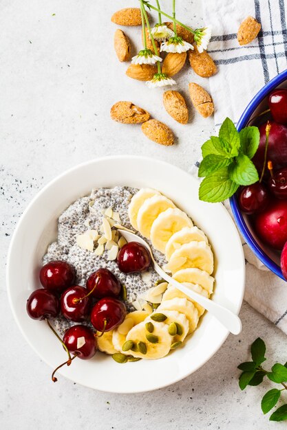 Pudding Chia z bananem, wiśnią i orzechami w białym talerzu.