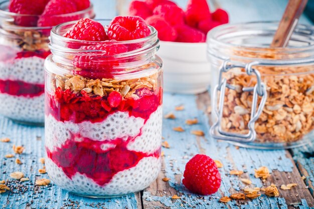 Pudding chia z granolą w sosie malinowym i świeżymi malinami na rustykalnym tle