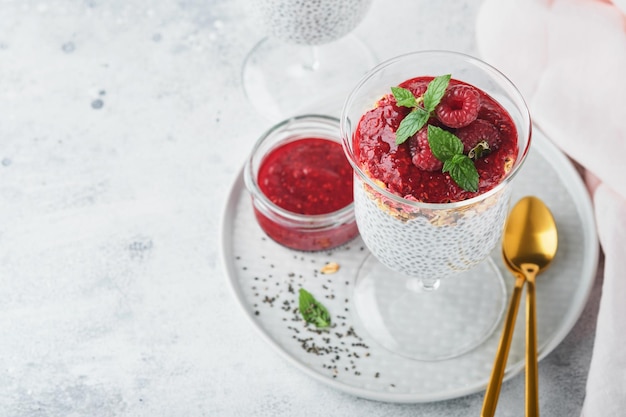 Pudding chia Zdrowy pudding chia waniliowy w szkle ze świeżymi malinami i miętą na białym tle Wegańskie zdrowe śniadanie