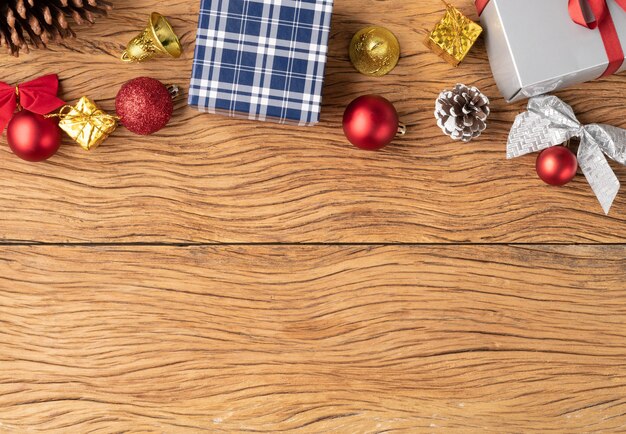 Zdjęcie pudełka na prezenty, bombki, dzwonek, szyszka i łuk nad drewnianym stołem. świąteczne dekoracje z miejsca na kopię.