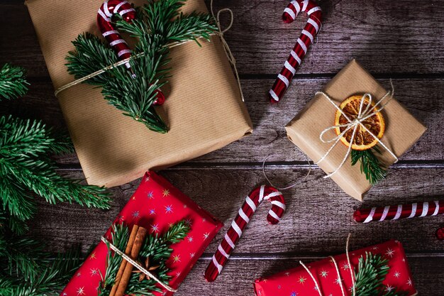 Pudełka na prezenty świąteczne z kraftem, czerwoną dekoracją i rolkami papieru, lizakami i gałązkami sosny