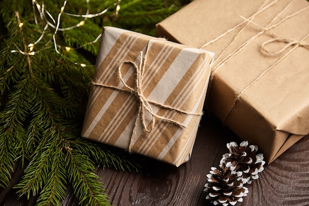 Pudełka Na Prezenty Z Bożonarodzeniowym światłem I Gałęzią Drzewa Z Szyszkami Na Brązowym Drewnianym Tle