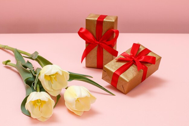 Pudełka na prezenty z pięknymi żółtymi tulipanami na różowym tle Koncepcja dawania prezentu na święta
