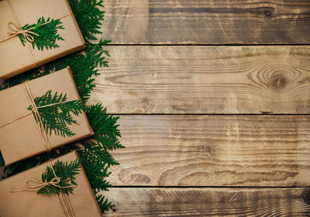 Pudełka zapakowane w papier kraft na drewnianym tle.Materiał ekologiczny. Ręcznie robione rzemiosło artystyczne. Boże Narodzenie i nowy rok.