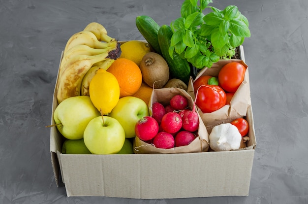 Pudełko darowizny ze świeżych owoców, warzyw i ziół na betonowym tle. Odpowiednie odżywianie. Dostawa zdrowej żywności do domu. Orientacja pozioma.