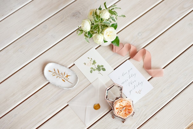 Pudełko na biżuterię z bliska rocznika biżuterii ślubnej na obrączki na drewnianym stole z życzeniami i wazon z kwiatami.