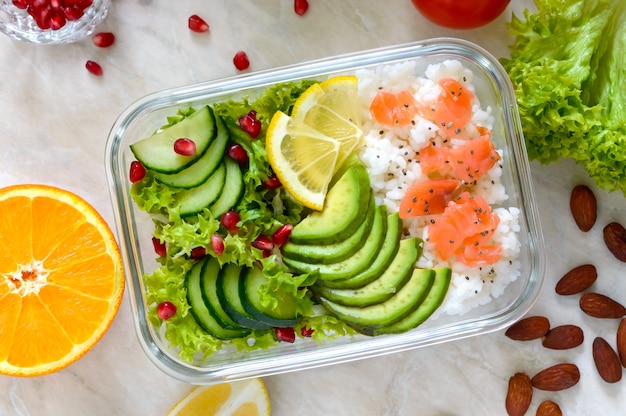 Pudełko na lunch: ryż, łosoś, sałatka z ogórkiem, awokado, warzywa. Jedzenie fitness. Szkolne pudełko na lunch