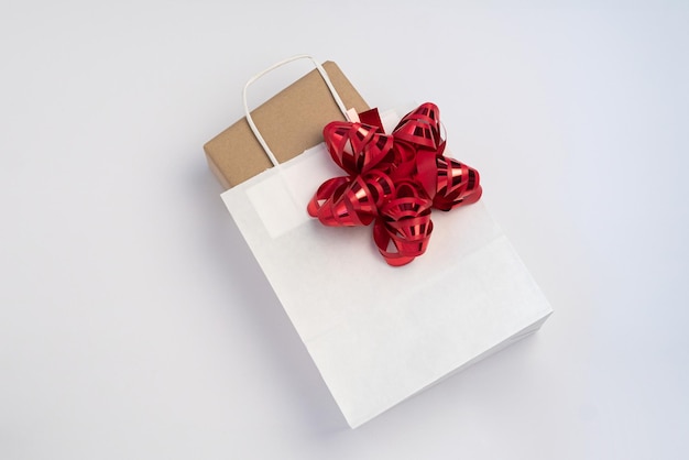 Pudełko na prezent w czystej białej papierowej torbie z czerwoną kokardką
