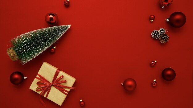 Pudełko na prezent z płaskim świeckim Boże Narodzenie bombki na czerwonym tle na święta. Widok z góry z miejscem na kopię