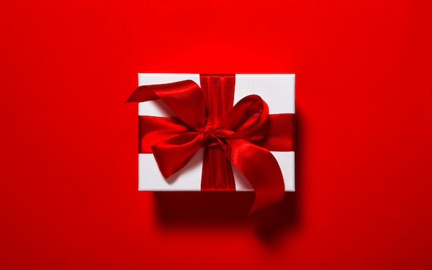 Zdjęcie pudełko prezentowe z kokardką na czerwonym tle