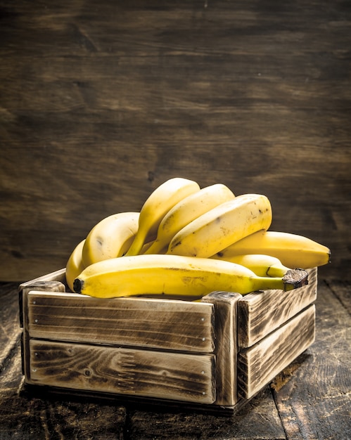 Pudełko świeżych bananów. Na drewnianym stole.