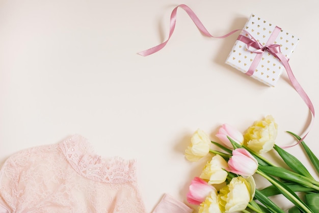 Pudełko upominkowe na odzież damską i kwiaty tulipanów Minimalistyczna kompozycja w pastelowych odcieniach beżu i różu Widok z góry płaska przestrzeń na kopię Koncepcja kobiecej mody urodzinowej i blogowania