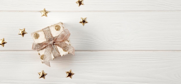 pudełko z prezentem świątecznym i złotymi gwiazdami na białym drewnianym tle widok z góry baner noworoczny