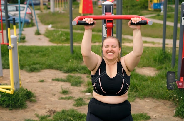 Pulchna, śmiejąca się kobieta uprawia sport na treningu na symulatorze