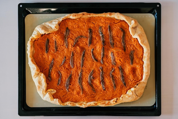 Zdjęcie pumpkin pie z sardynkami leży na arkuszu do pieczenia na górnym widoku stołu