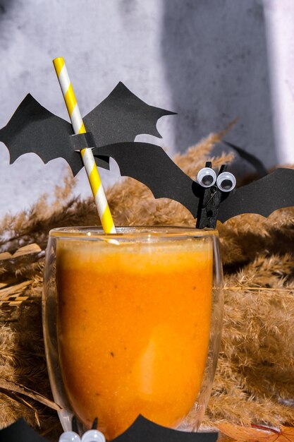 Pumpkin smoothie spiced latte autumn drinks for halloween decorations with bat on straw holiday